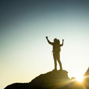 Shot of a man with arms raised and enjoying the of the montains at sunset